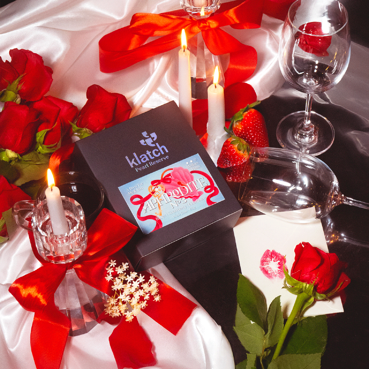 Aphrodite No 3 Peal Reserve Coffee laying on white satine with red roses, strawberries, candle light and wine glasses.