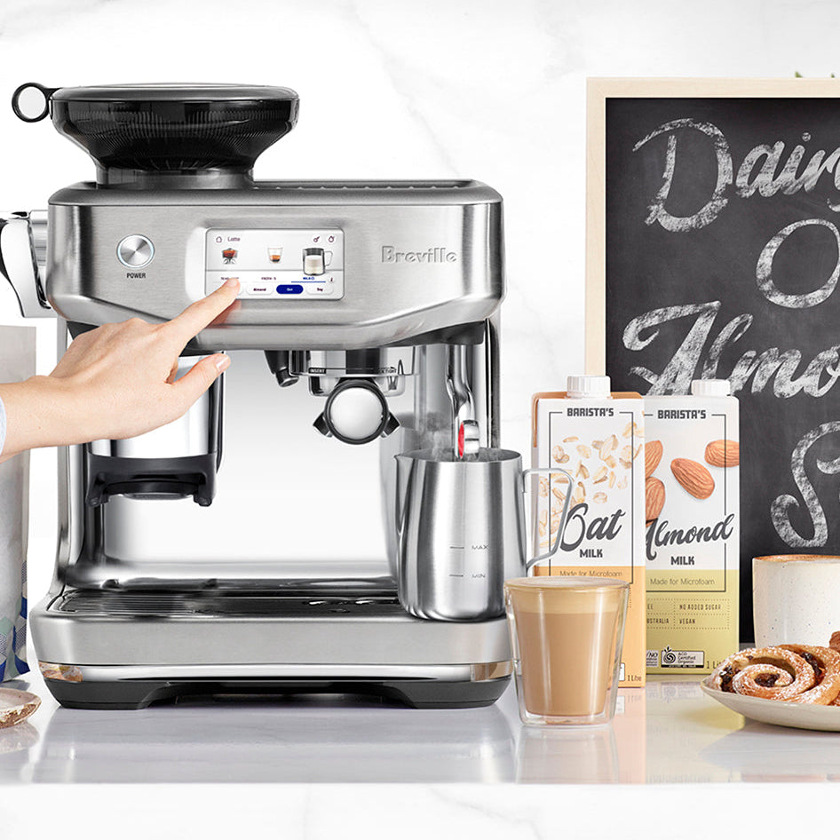 Breville Barista Impress Touch Espresso machine on a kitchen counter with a person interacting with it.