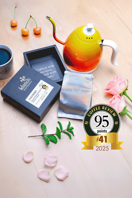 Pearl Box with a kettle, white cherries, spearmint, pink roses, and a coffee review badge on a wooden table.