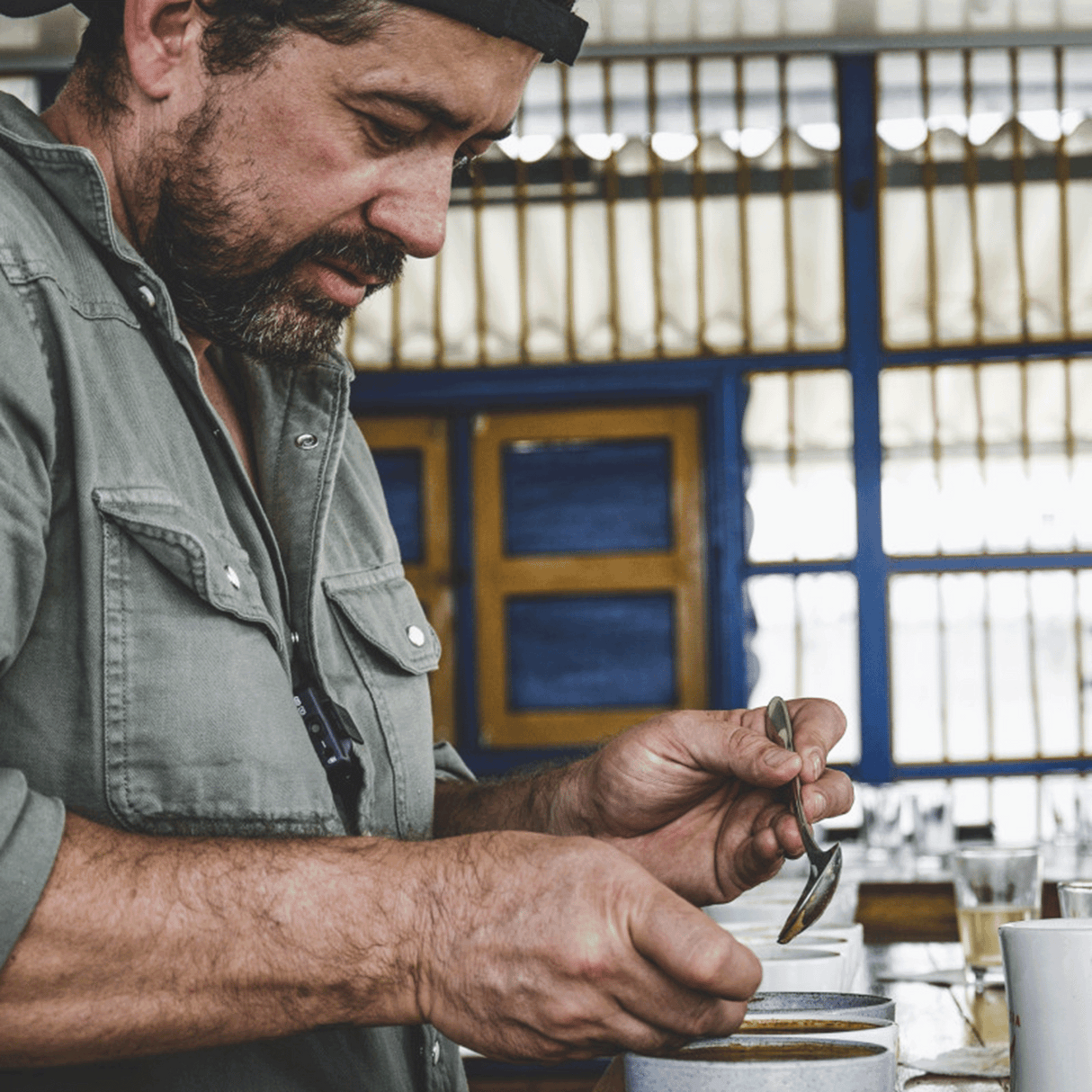 At Finca Campos Hermoso with Edwin cupping his coffees holding cupping spoon over cup.