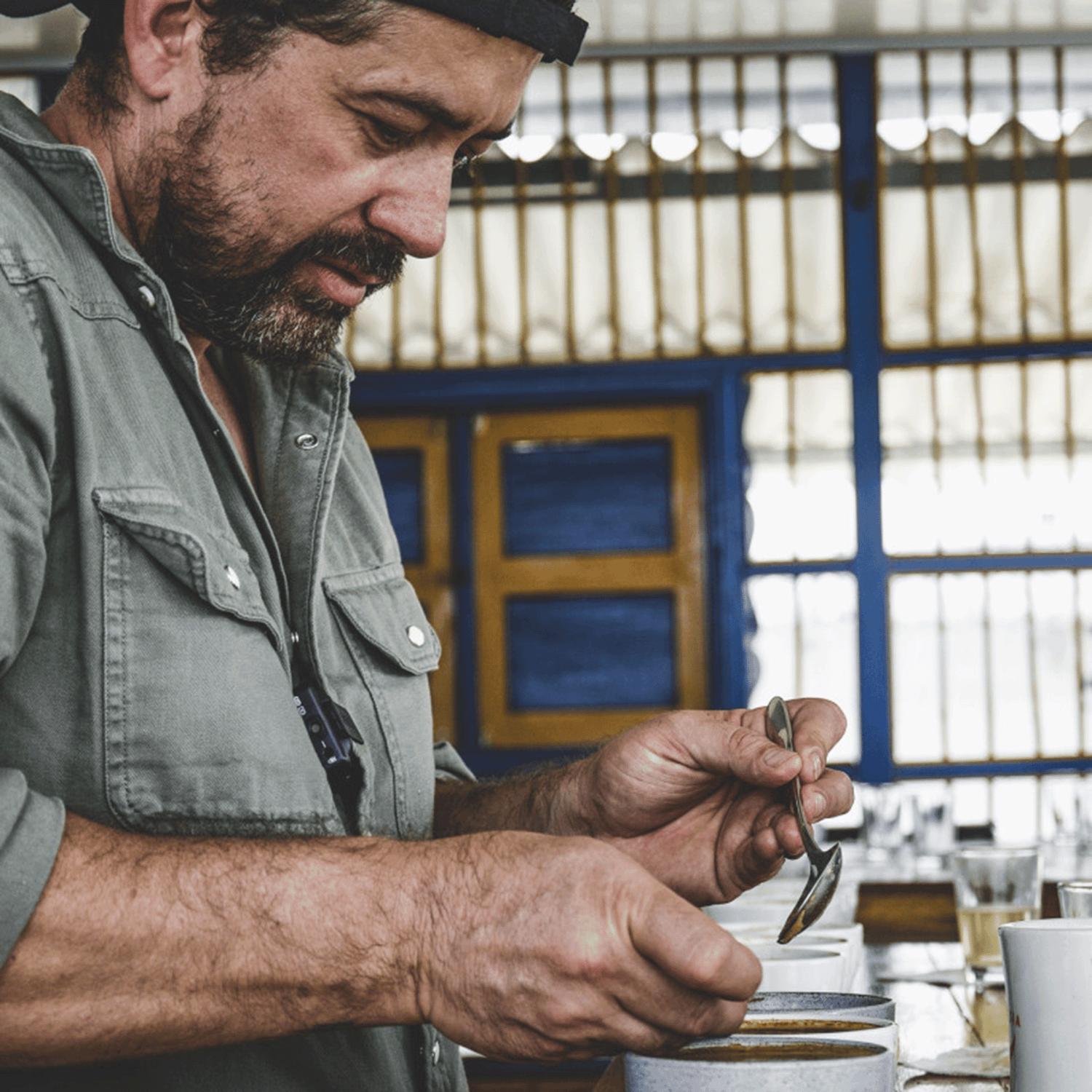 At Finca Campos Hermoso with Edwin cupping his coffees holding cupping spoon over cup.