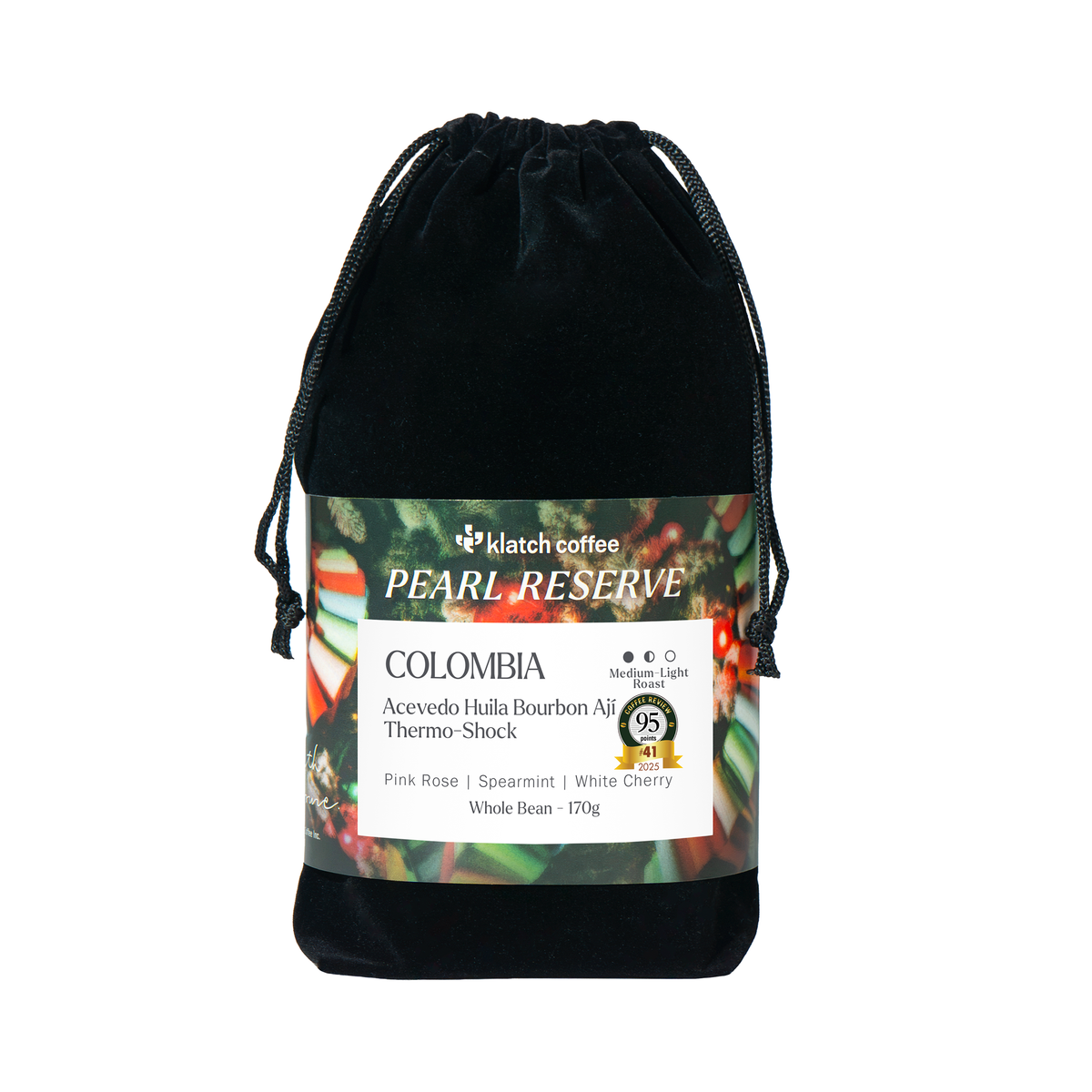 A black velvet drawstring pouch containing Klatch Coffee Pearl Reserve Colombia whole bean coffee, with a detailed product label wrapped around the middle, set against a plain white background.