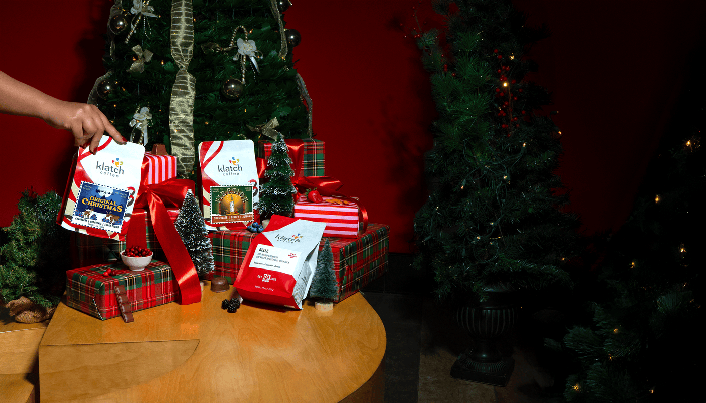 December Club coffees with Christmas gift setup with wrapped presents and a tree in a festive setting.