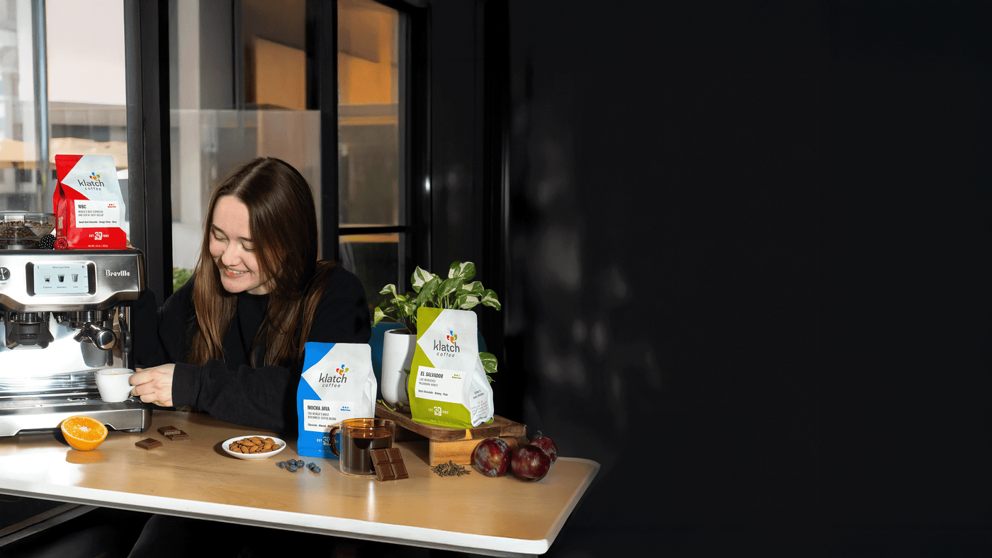 Woman making espresso with WBC, other club coffees on table.
