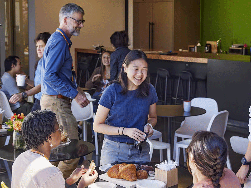 MBC BioLabs team members gathering and enjoying pastries together in a shared office space.