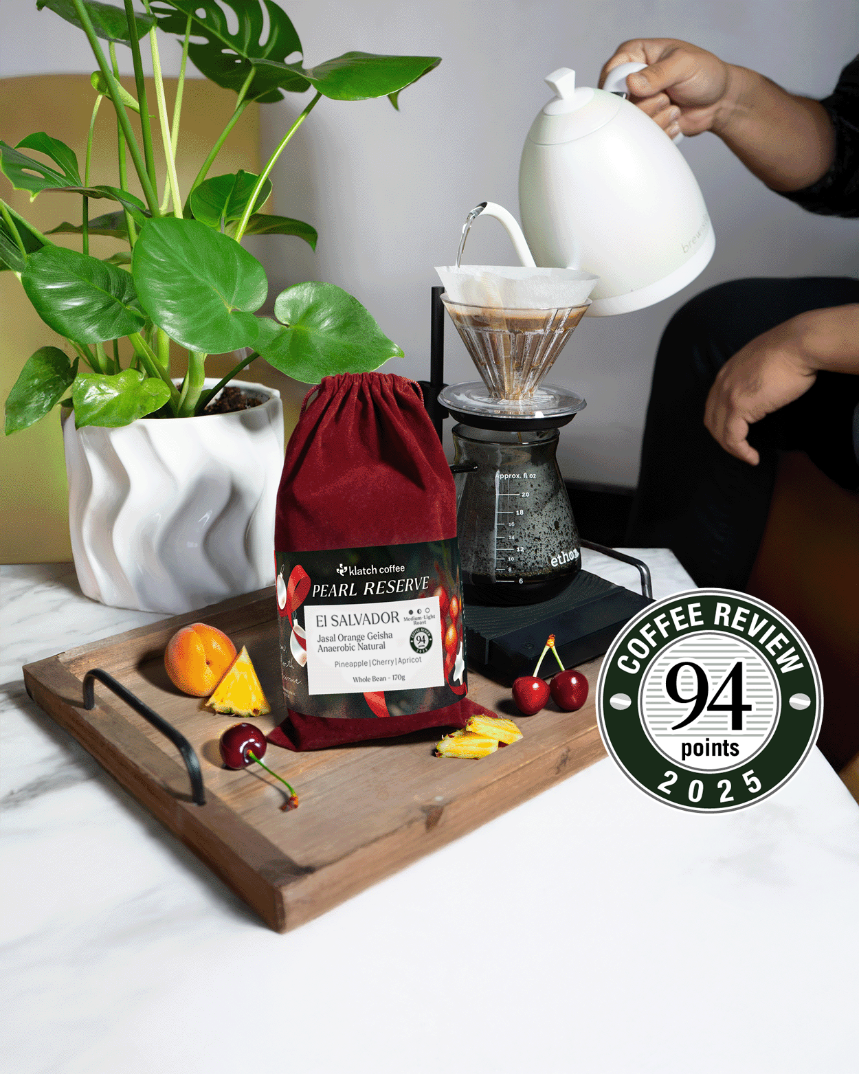 El Salvador Jasal Orange Red Velvet coffee bag on a tray surrounded by pineapple, cherries, and apricots.