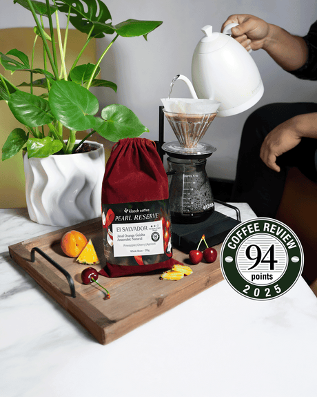 El Salvador Jasal Orange Red Velvet coffee bag on a tray surrounded by pineapple, cherries, and apricots.