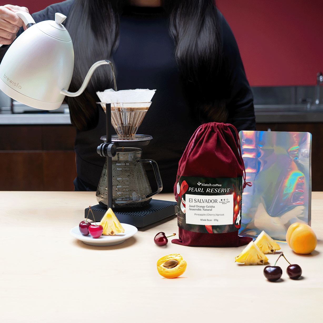 Person pouring coffee using a pour-over setup with a bag of Pearl Reserve coffee on a table.