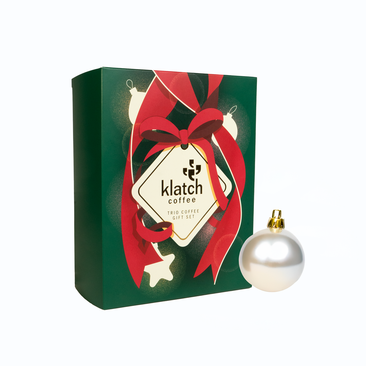 Holiday Gift box with a red ribbon and 'Klatch Coffee' label with decorative a pearl ornament on a white background.