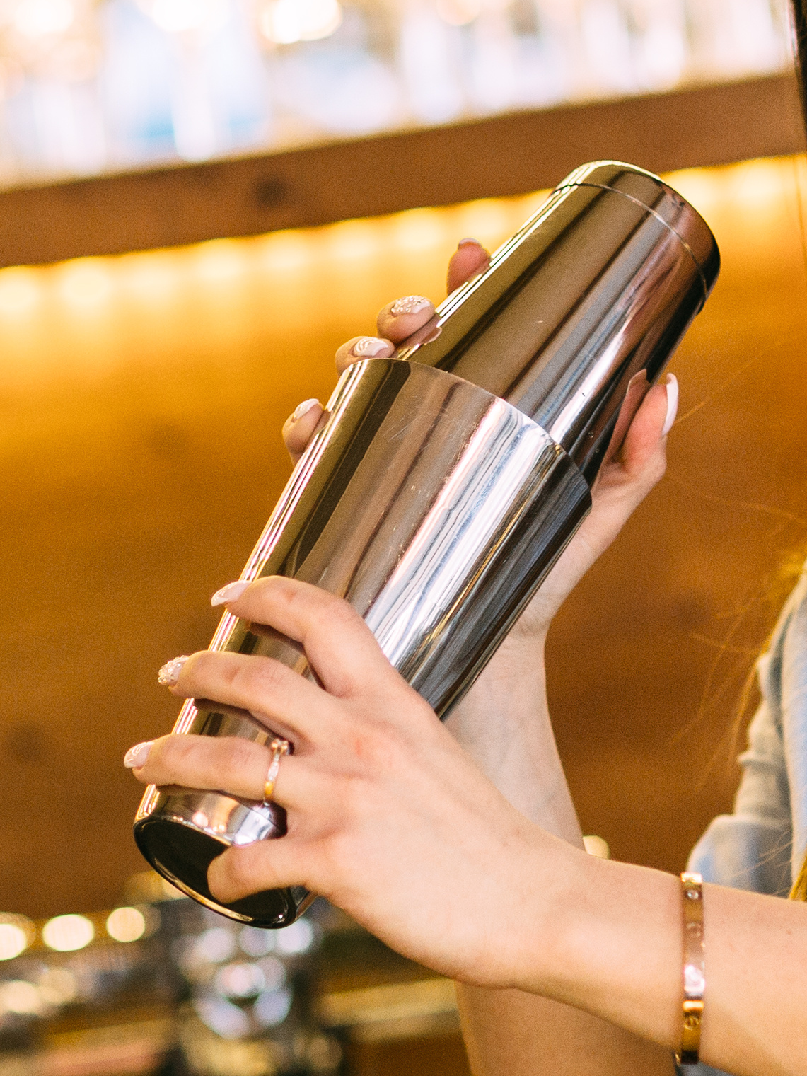 Hand holding a metallic shaker against a blurred indoor background