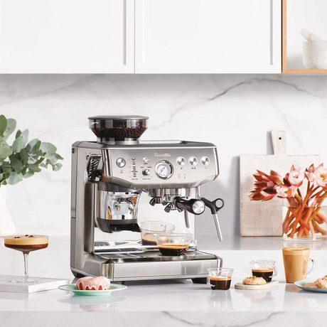 Breville Barista Express Impress Espresso Machine on a kitchen counter with coffee and decor