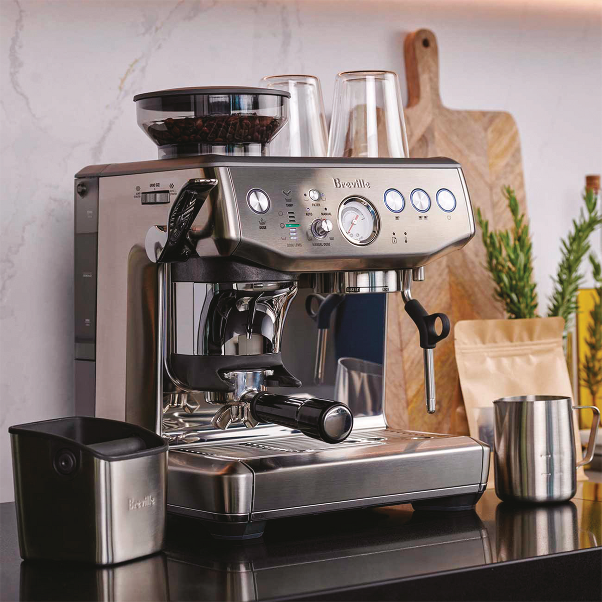 Breville Barista Express Impress Espresso Machine on a kitchen counter with Breville knock box and pitcher