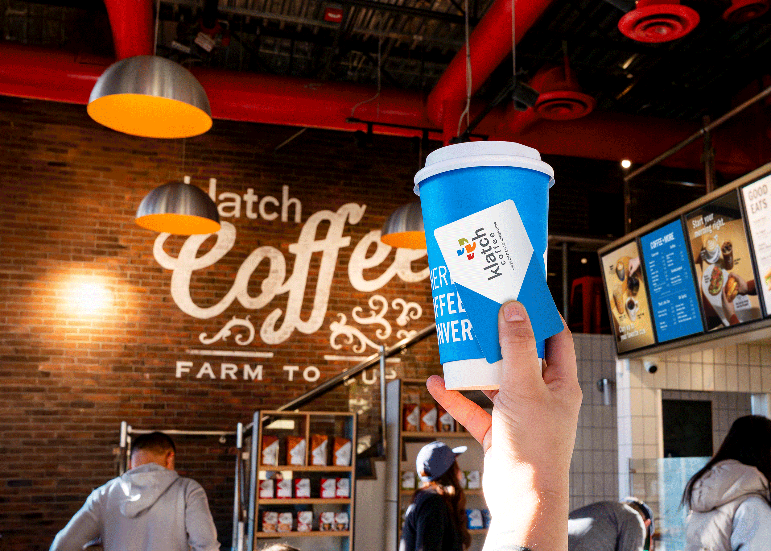 Person holding a blue coffee cup and a gift card that says “Klatch Coffee” in a café setting.