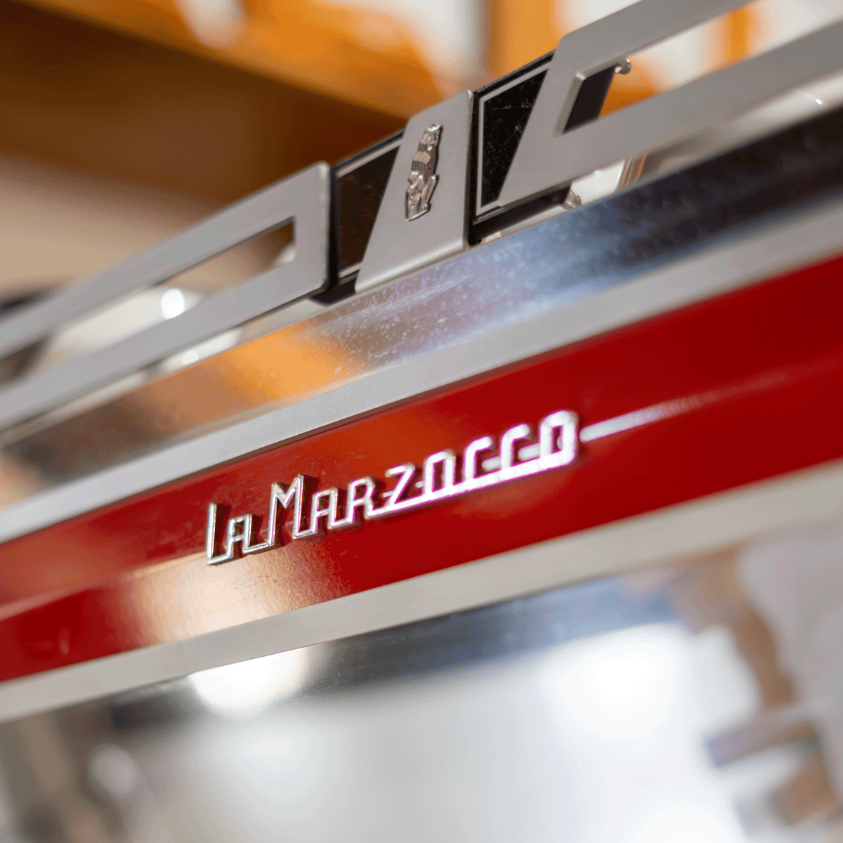 Close-up of a red La Marzocco commercial espresso machine featuring the brand’s chrome logo.