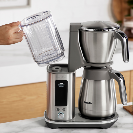 Breville  Luxe™ Brewer Thermal Drip Coffee Machine with a person pouring water into it on a kitchen counter.
