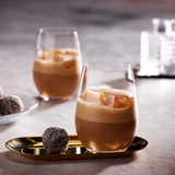 Two glasses of iced latte drinks with a dessert on a table