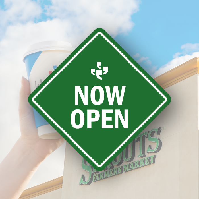 A green diamond-shaped vector sign with the Klatch Coffee logo at the top and “Now Open” beneath it, placed over a photo of Sprouts and a Klatch sign.