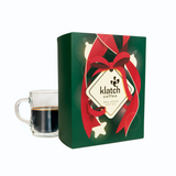 Holiday Gift set box with red ribbon and 'Klatch Coffee' branding next to a glass of coffee.