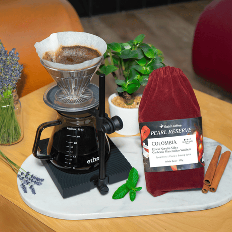Coffee brewing setup with a coffee filter, coffee grinder, and a bag of coffee on a wooden table.