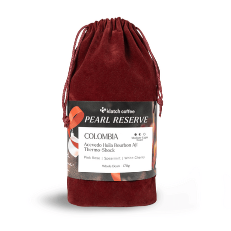 Red velvet drawstring bag with Klatch Coffee Pearl Reserve Colombia label on a white background