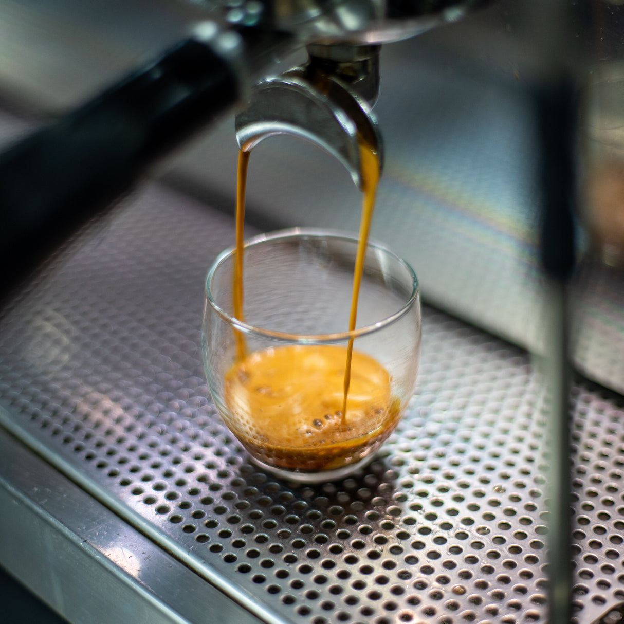 Centennial espresso extraction into glass cup.