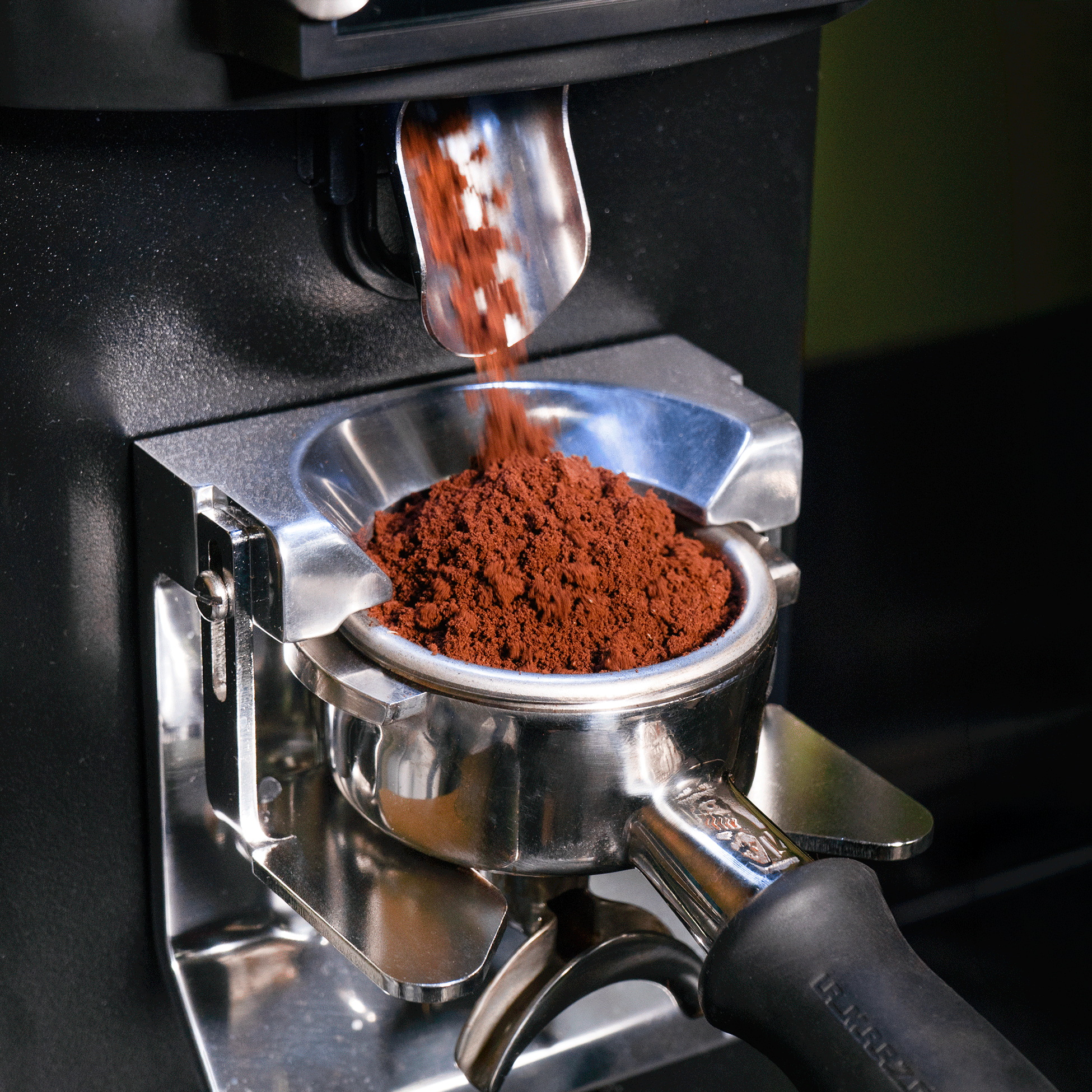 Coffee grounds dispensing into a portafilter from a grinder.