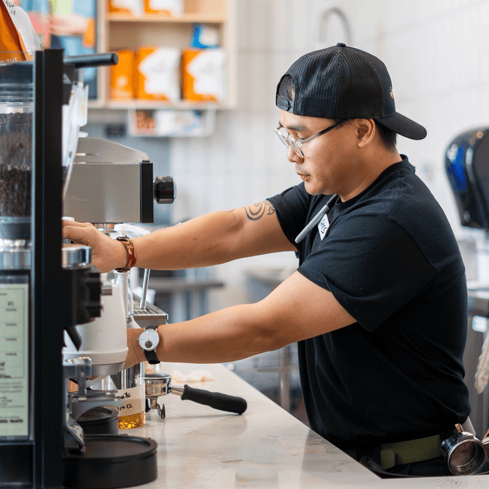 Barista steaming milk in a cafe setting. 
