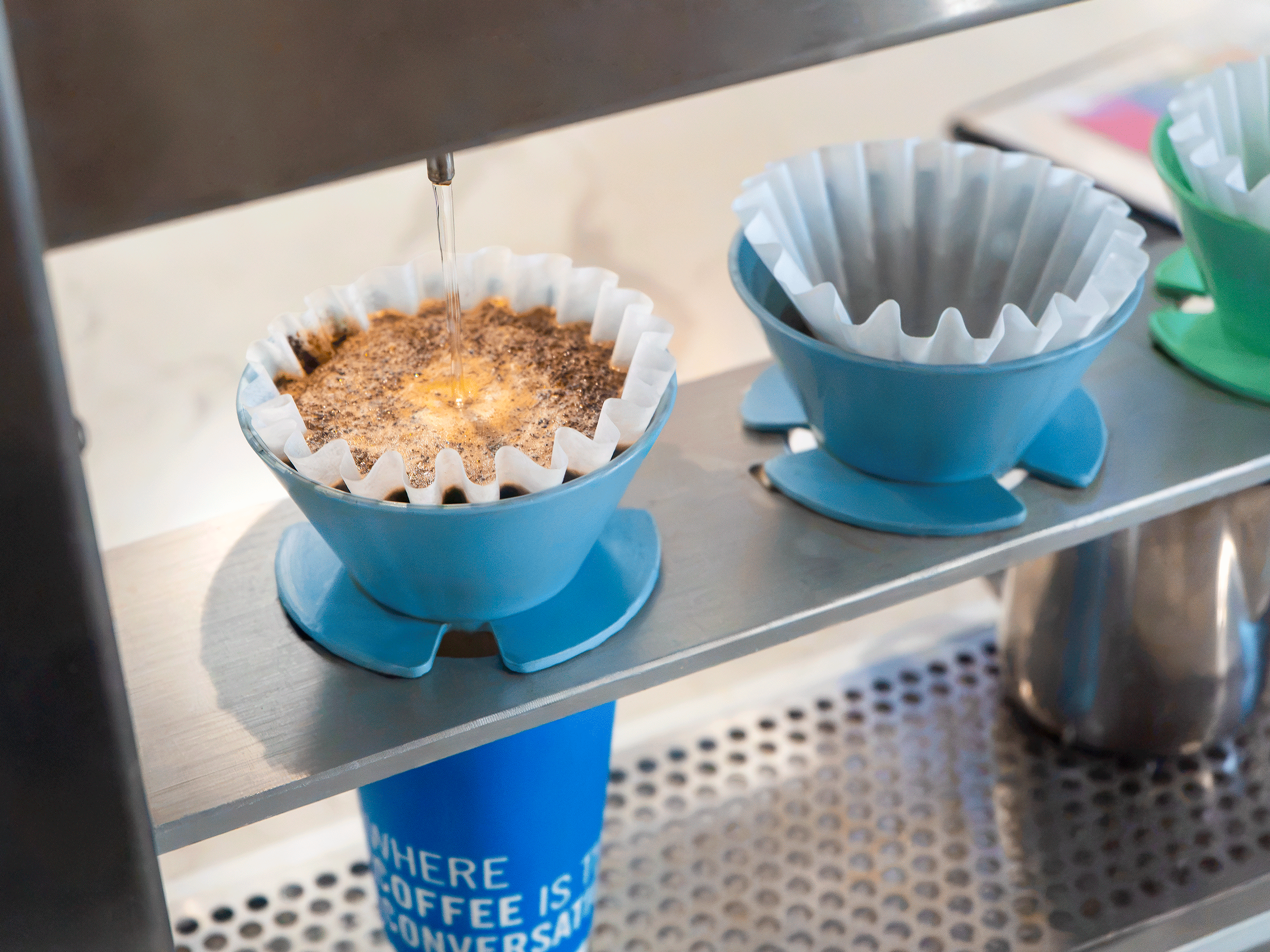 Close-up of a Poursteady brewer pouring water into an April dripper filled with freshly ground coffee.
