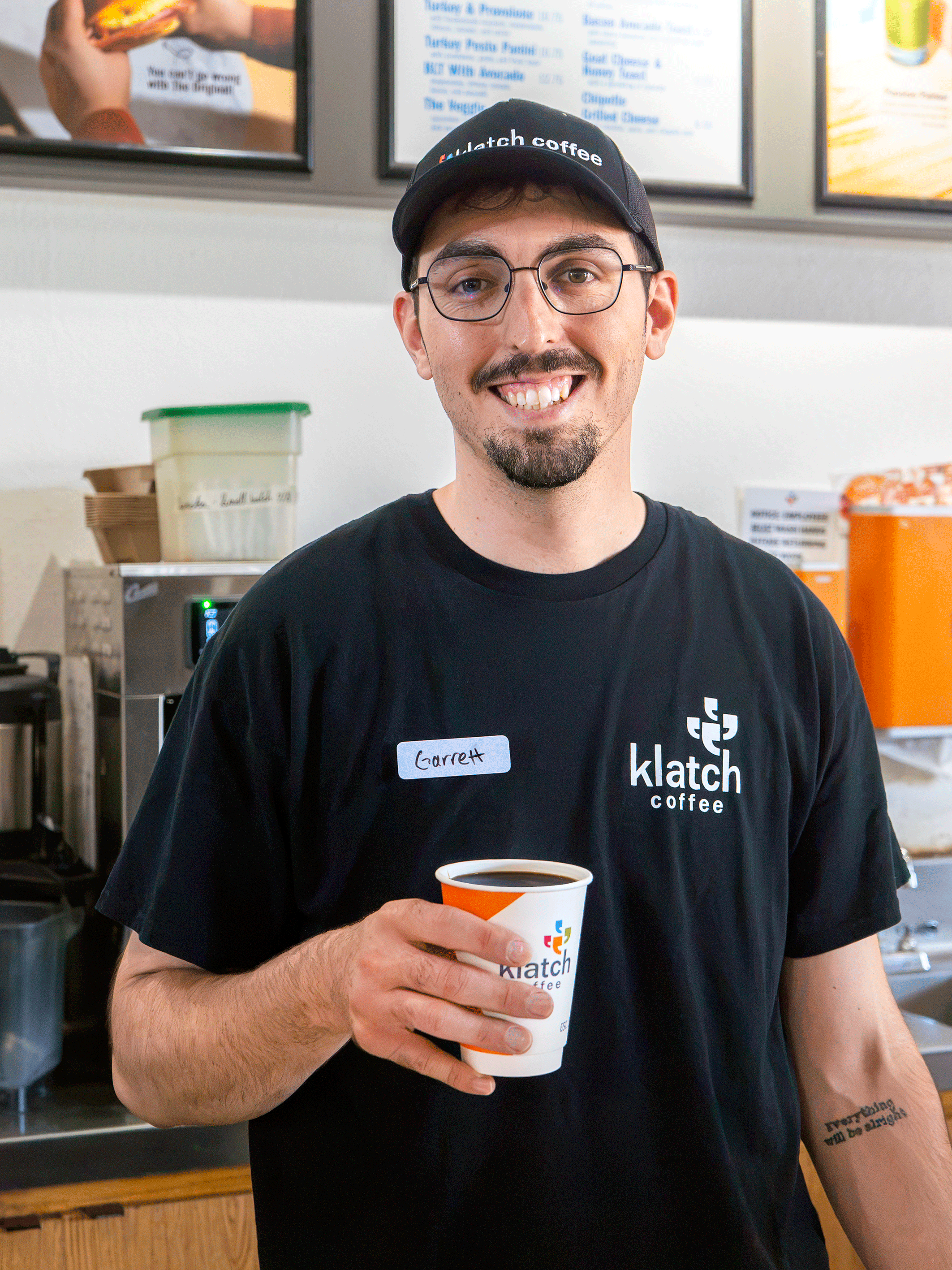 Barista holding a cup of freshly brewed black coffee inside a café.