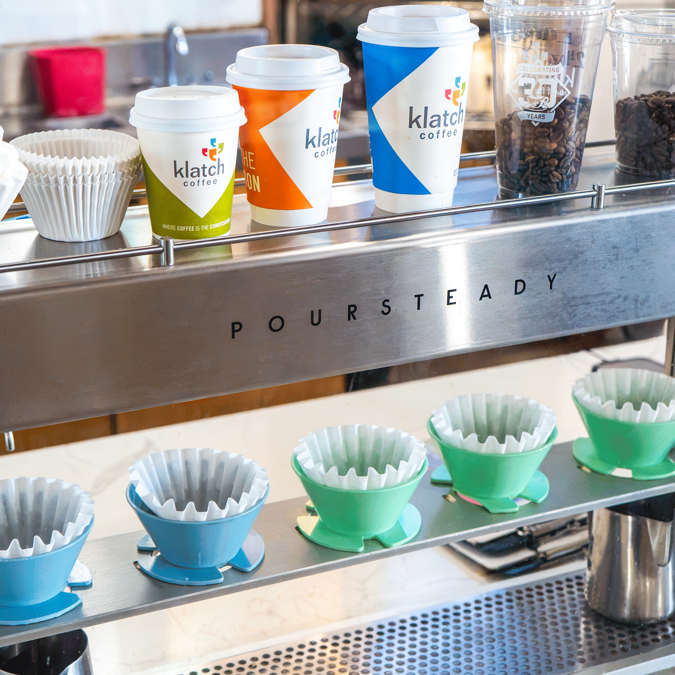 Close-up of a Poursteady automated pour over brewer with a colorful Klatch Coffee cup on top.