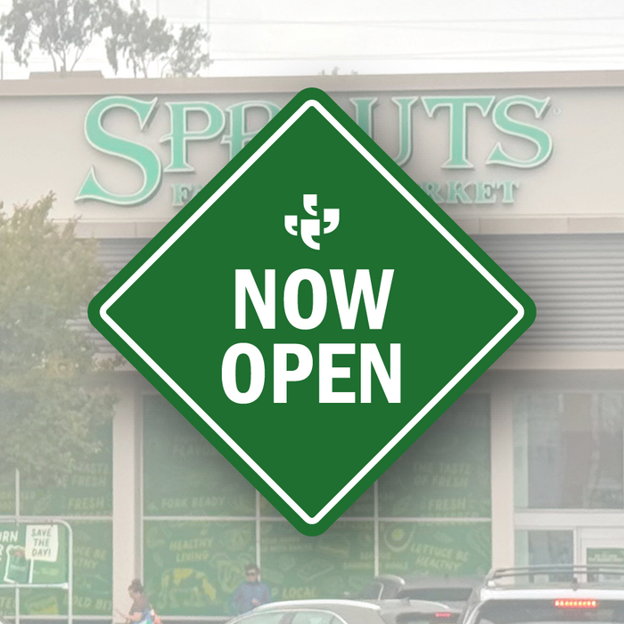 A green diamond-shaped vector sign with the Klatch Coffee logo at the top and “Now Open” beneath it, placed over a photo of Sprouts. 