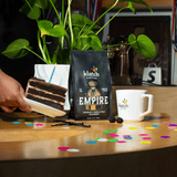 Klatch coffee Empire bag with a slice of Birthday cake and a mug on a table.