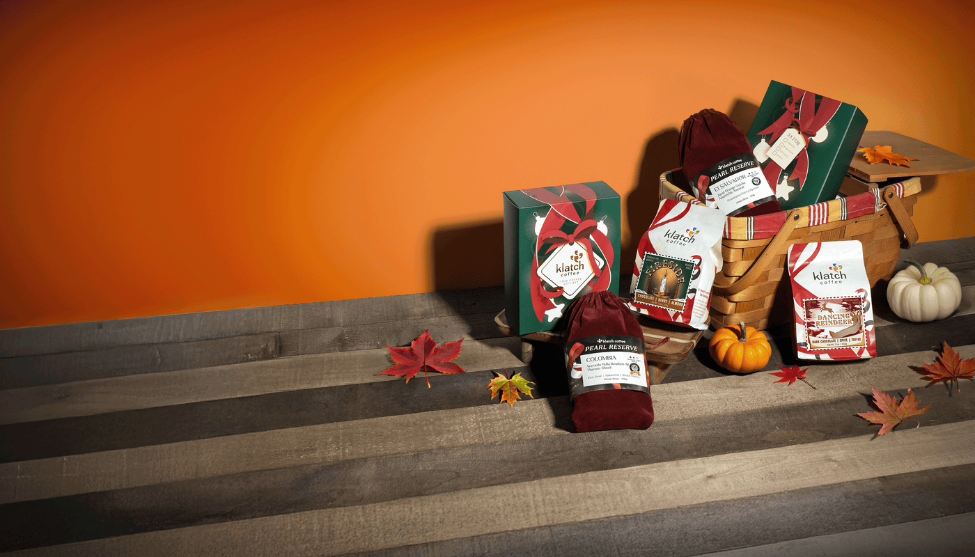 Gift basket with klatch wine and products on a wooden surface with pumpkins and autumn leaves.