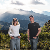 Rachel Peterson and brother Daniel Peterson standing in a scenic outdoor setting with coffee trees and mountains in the background.