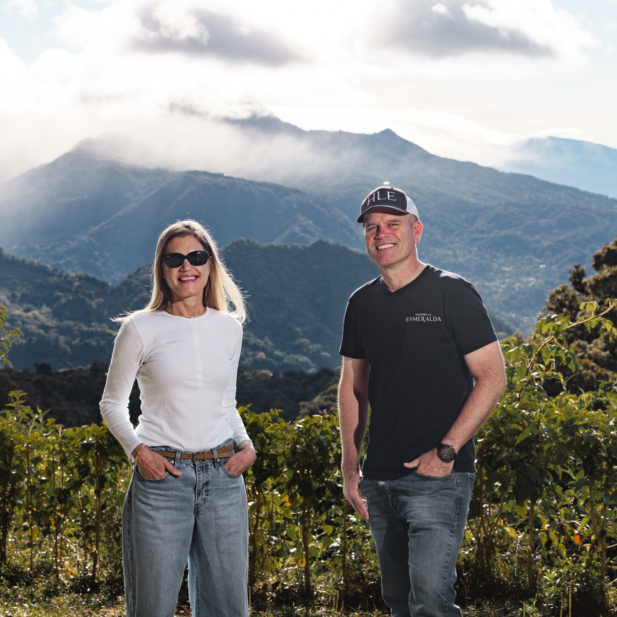 Rachel Peterson and brother Daniel Peterson standing in a scenic outdoor setting with coffee trees and mountains in the background.