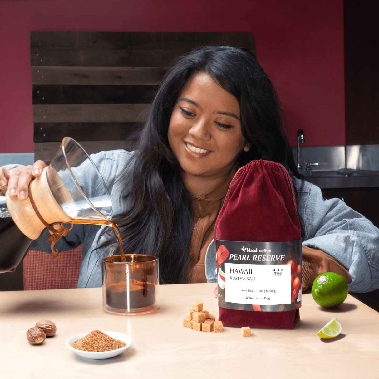 Woman pouring coffee into a glass with a Pearl Reserve coffee bag on a table.