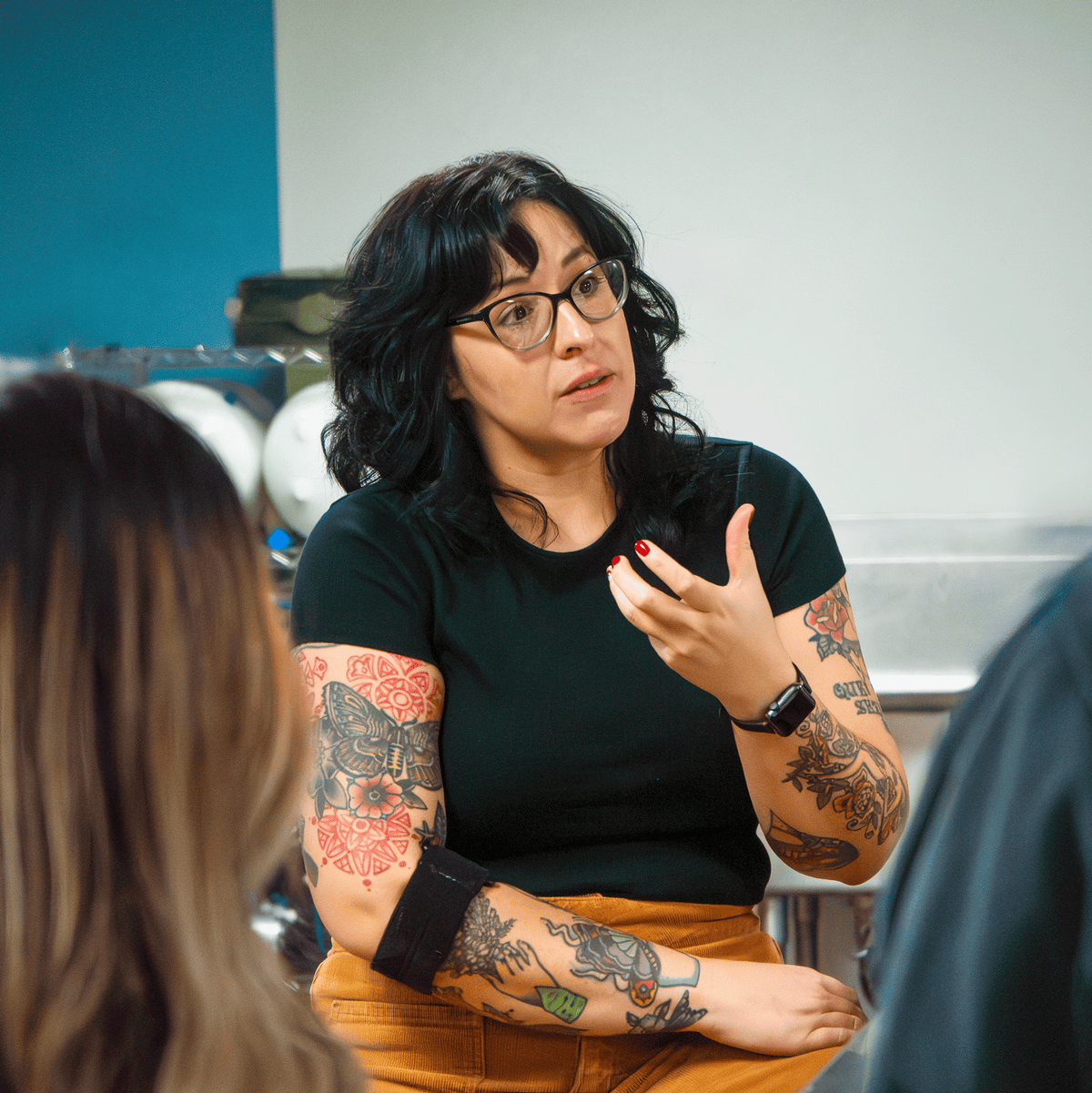 Coffee educator speaking and gesturing during a hands-on coffee training session with students.