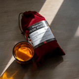 Red velvet bag with a Kenya Berg Wu label next to a shot of espresso in an orange cup.