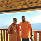 Mike Perry and Andres Salaverria standing on a wooden deck with a scenic background in El Salvador.