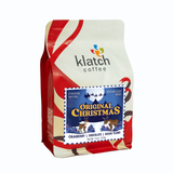 Holiday white and red ribbon graphics on Klatch Coffee Original Christmas coffee bag on a white background.