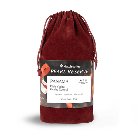 Red velvet drawstring bag with a label for klatch coffee Pearl Reserve Panama  Elida Vuelta  Geisha on a white background