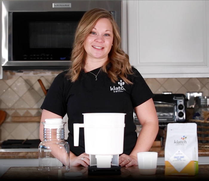 Holly Perry standing in a kitchen demonstrating how to use a toddy brewer.
