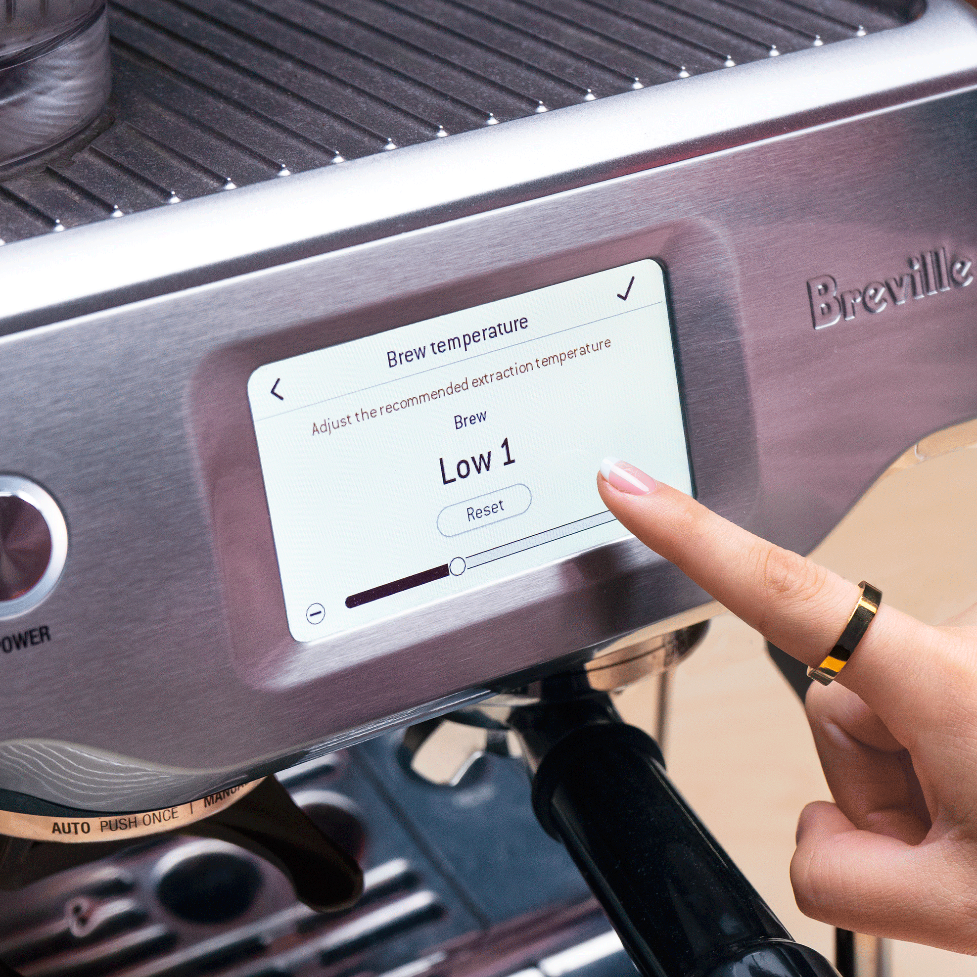 Finger hovering over the temperature adjustment screen on a Breville espresso machine.