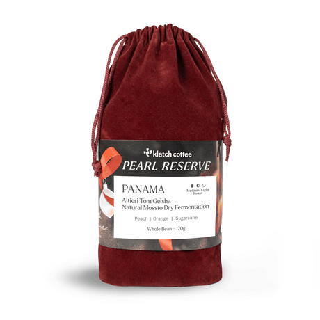 Red velvet drawstring bag with a label for klatch coffee Pearl Reserve Panama on a white background