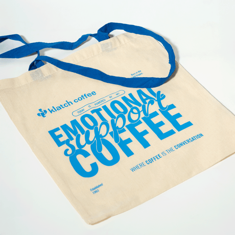 Beige tote bag with blue text and branding on a white background