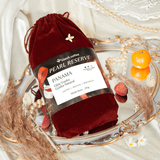 Red velvet drawstring bag with Panama Elida Vuelta Geisha coffee label on a decorative mirror tray with fruits.