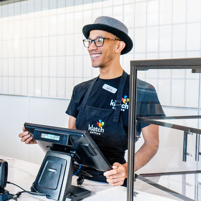 Barista smiling while standing at the register.
