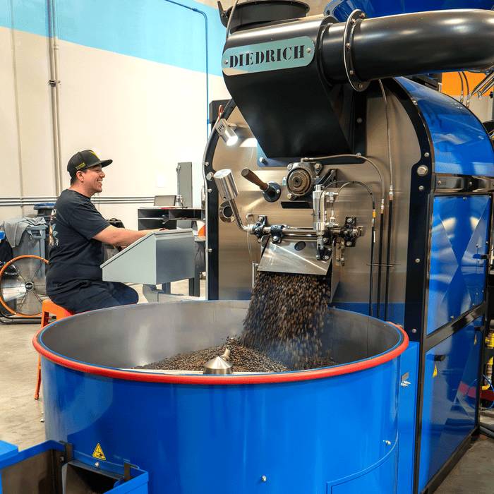 Person operating a coffee roasting machine in a factory setting