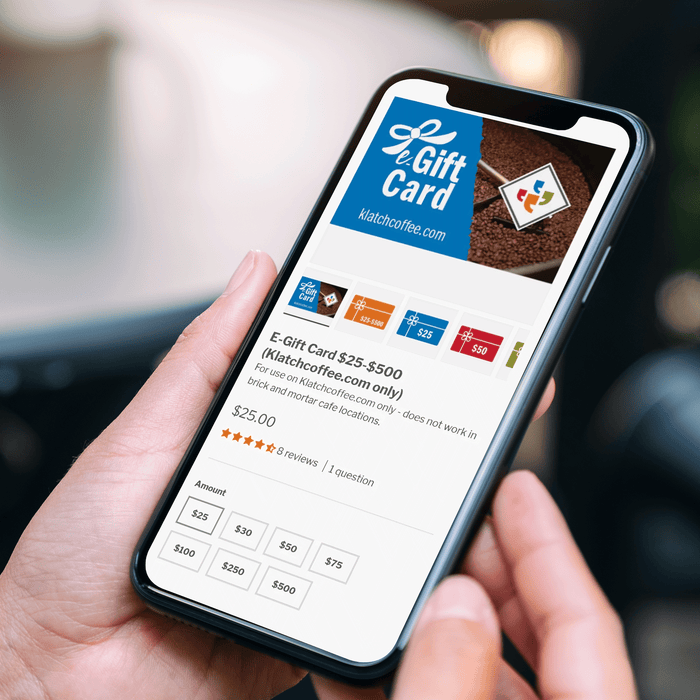 Close-up photo of someone holding a smartphone displaying the gift card page of the Klatch Coffee website.