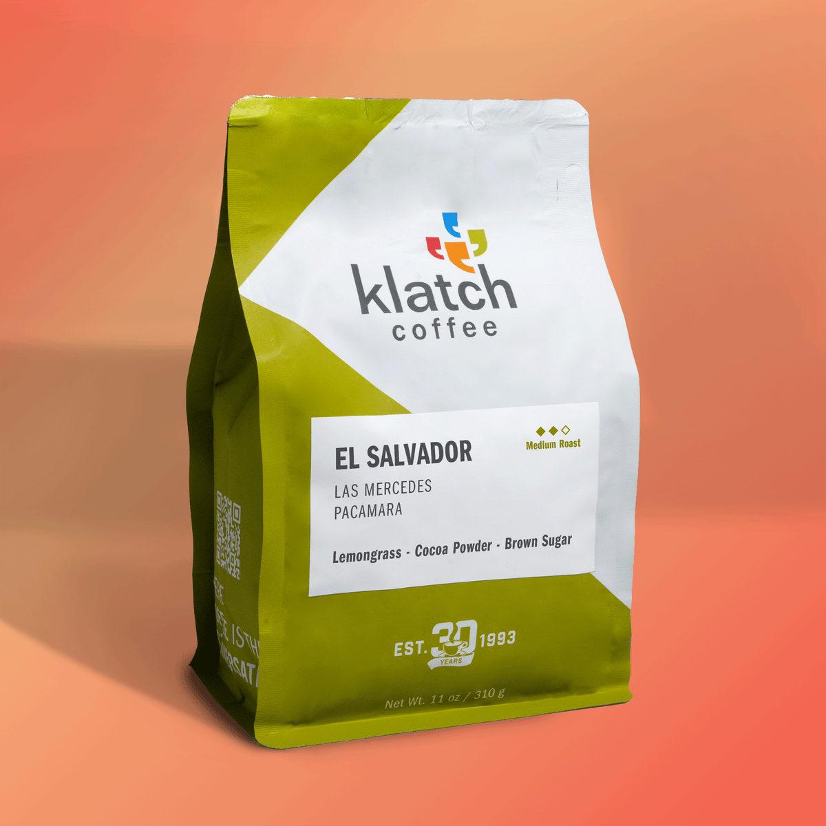 Bag of Klatch Coffee El Salvador Las Mercedes Pacamara medium roast featuring notes of lemongrass, cocoa powder, and brown sugar against a warm orange background.